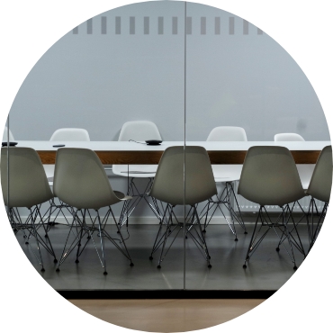 An empty conference room in an office setting behind glass walls.