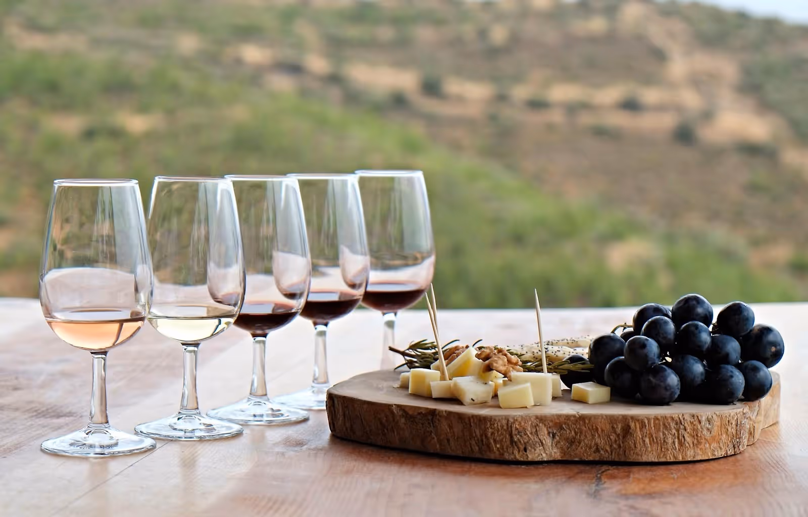 A group of wine glasses and a platter of cheese and grapesAI-generated content may be incorrect.