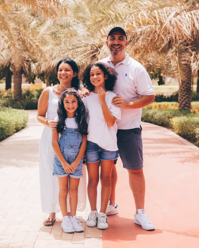 A family smiling and standing in a park