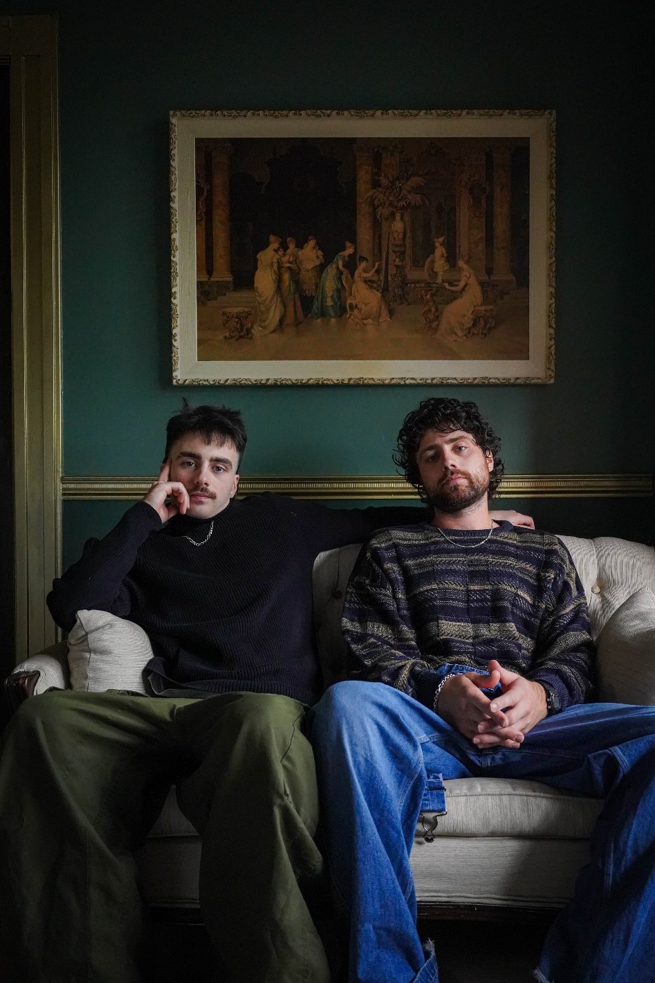 Band of two members sitting on a couch.