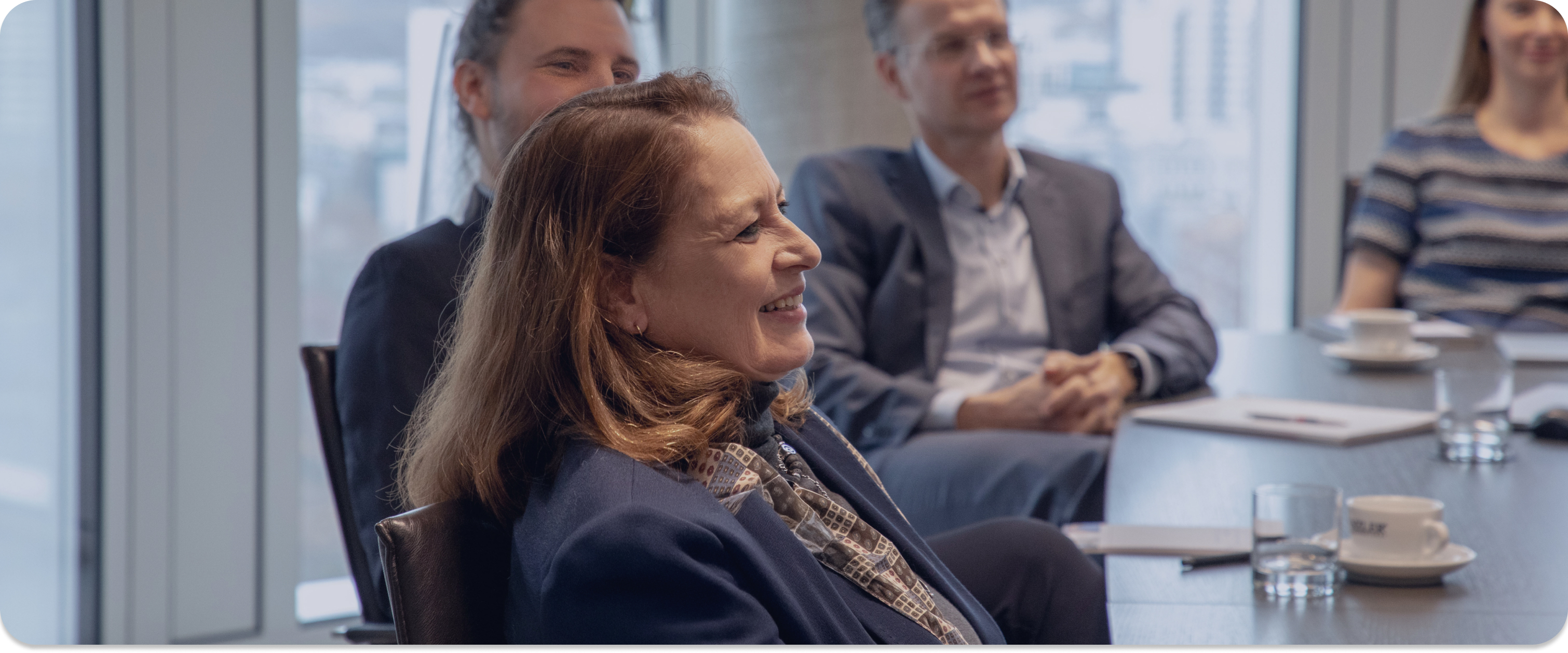 Porträt: Lächelnde Business-Frau mit Brille & grauen Haaren im Blazer.