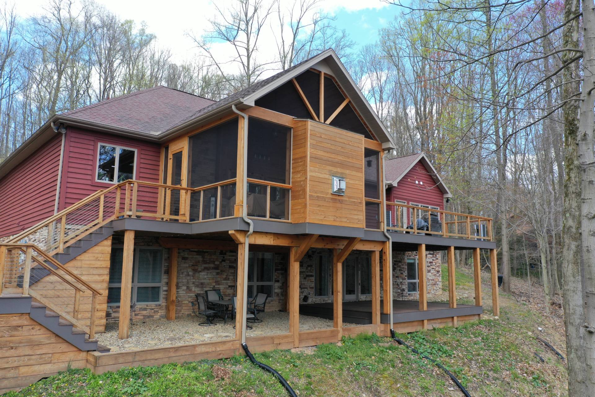 Screened porch with outdoor fireplace, servant window, cable rails, and cedar trim.