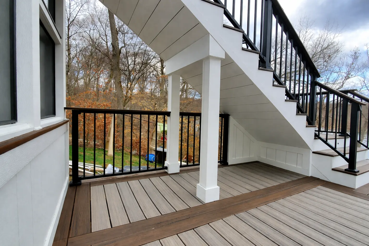 Deck stairs on composite deck with pvc trim and black aluminum handrails.