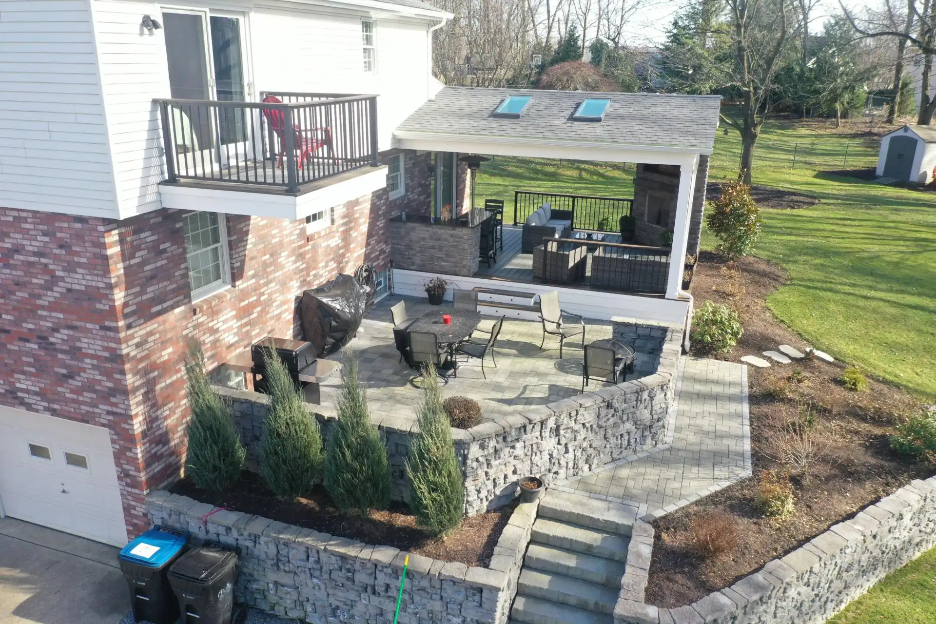 Covered deck with fireplace and patio with seating wall in Sewickley