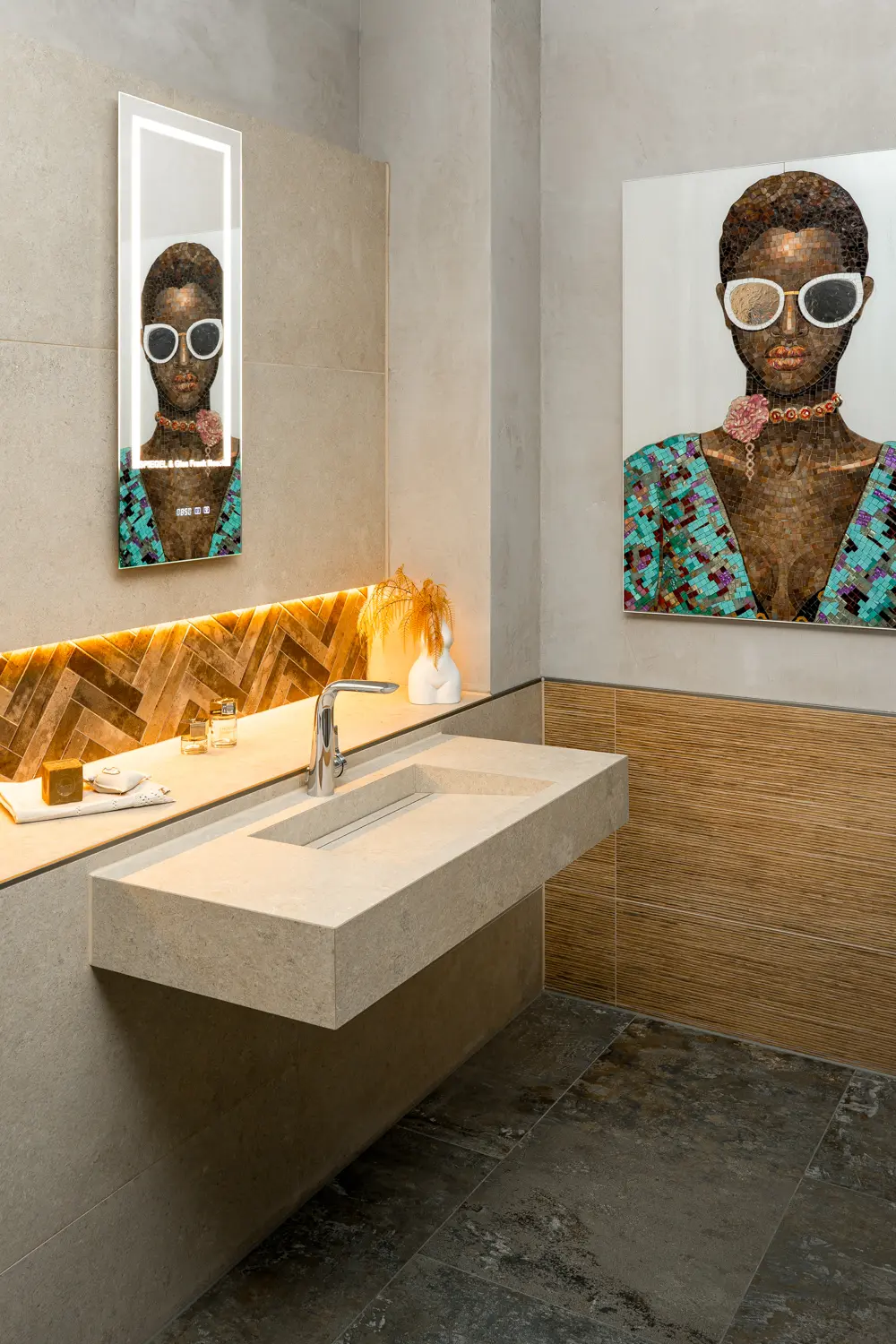 Modernes Badezimmer mit rechteckigem Steinwaschbecken, beleuchtetem Spiegel und Kunstwerk einer Frau mit Sonnenbrille.