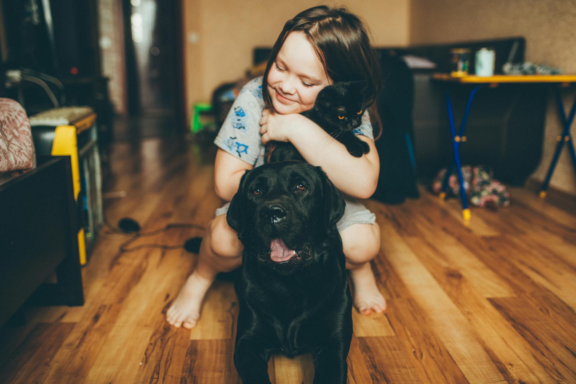 A girl with her pet dog and cat on a vinyl floor.