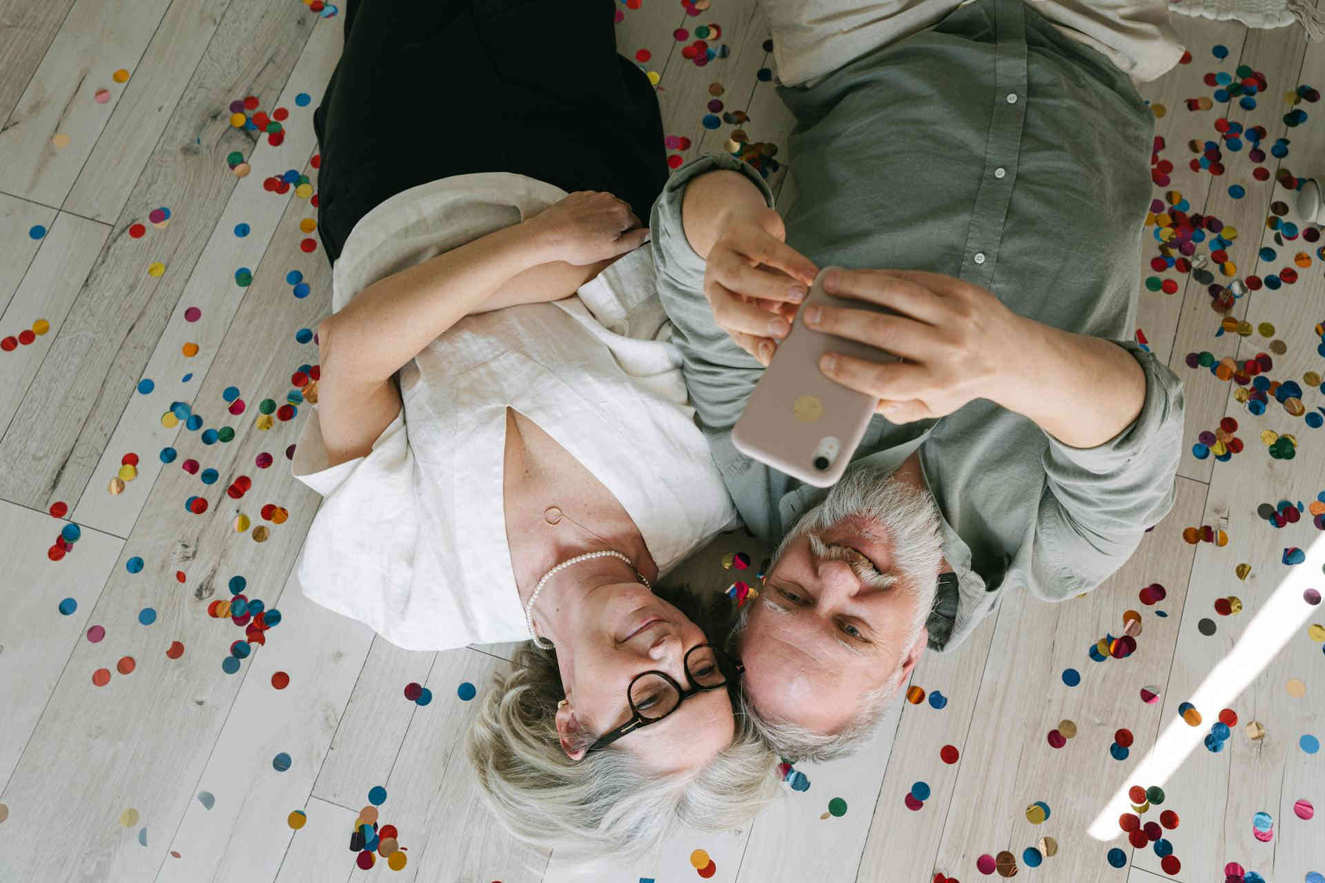 An elderly couple lays next to each other on their vinyl floor looking happy and contented about life. 