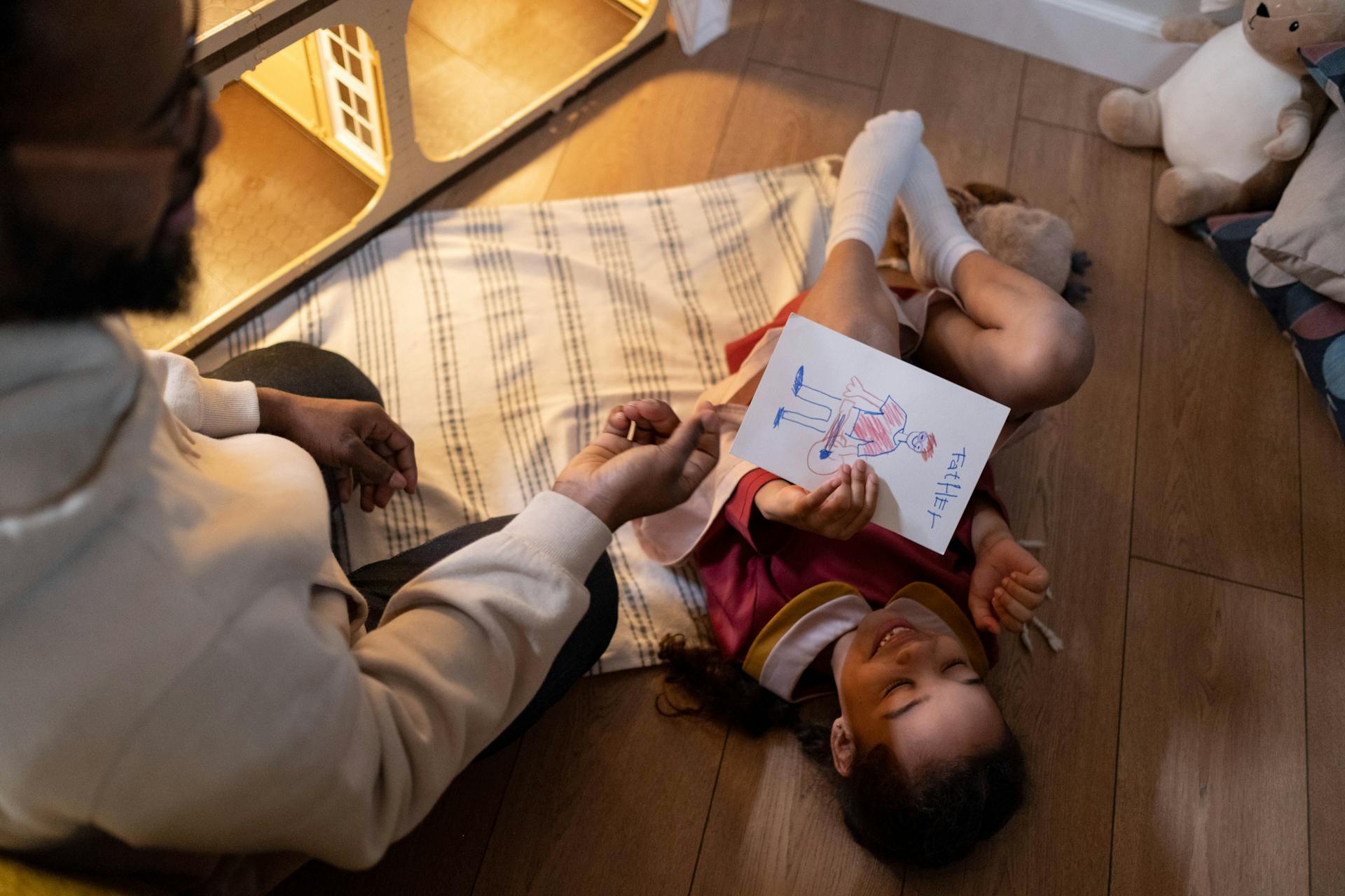 A girl lays on a vinyl floor while playing with her dad.