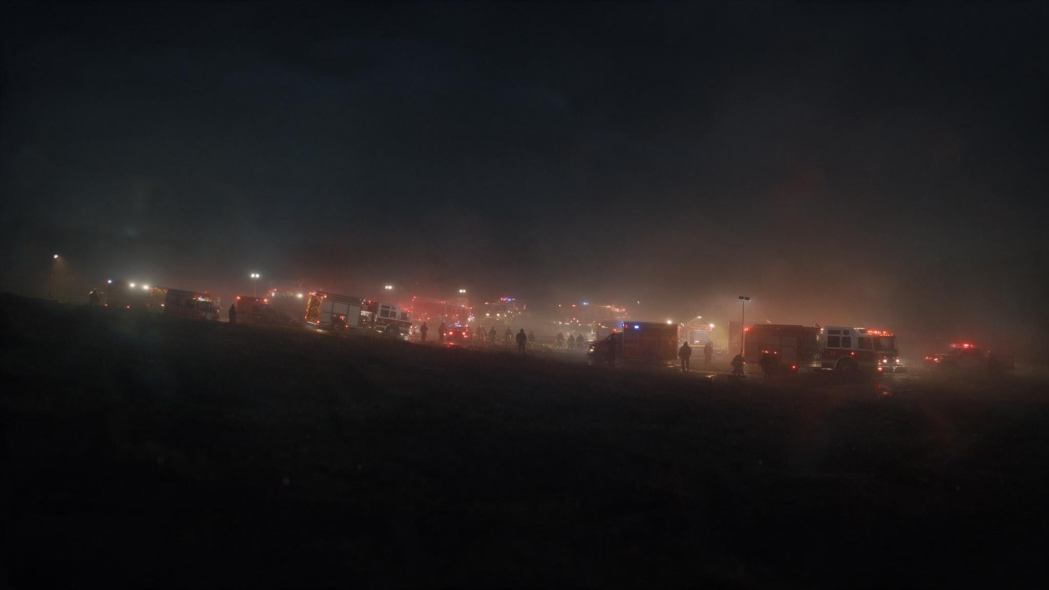 Emergency vehicles staged at night during a large rural incident.