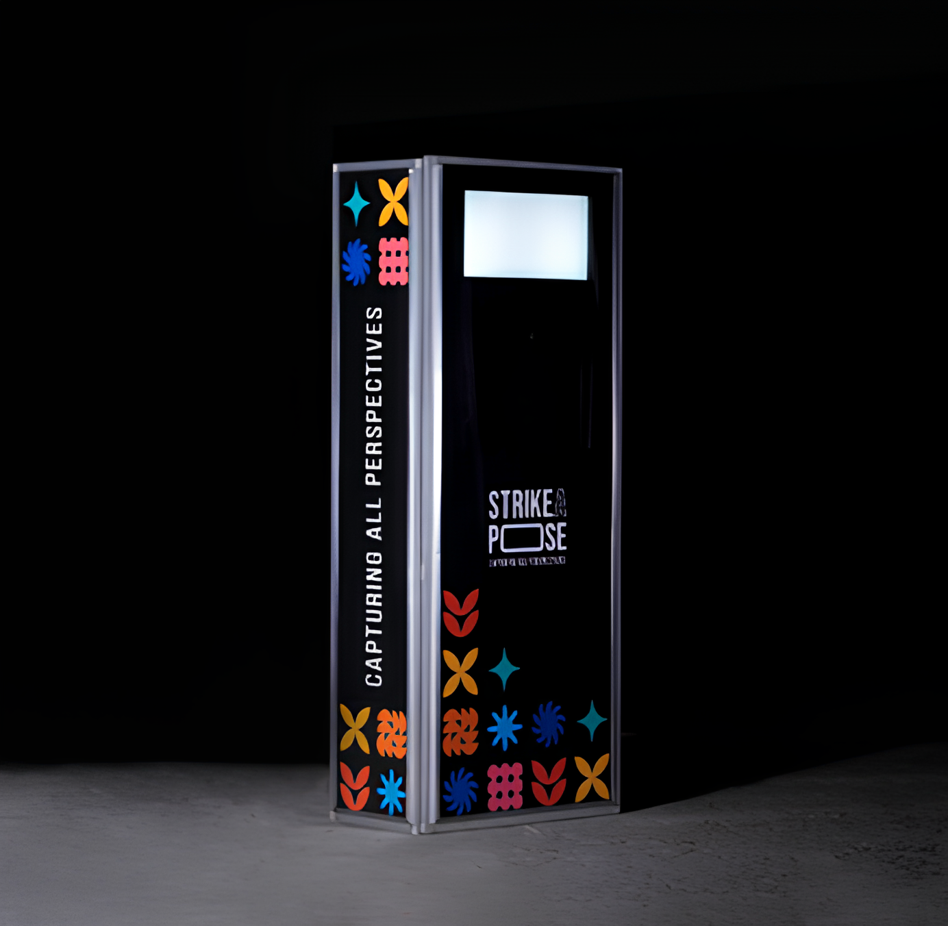 Photo booth with colorful floral patterns and text reading 'CAPTURING ALL PERSPECTIVES' and 'STRIKE A POSE' on a dark background.