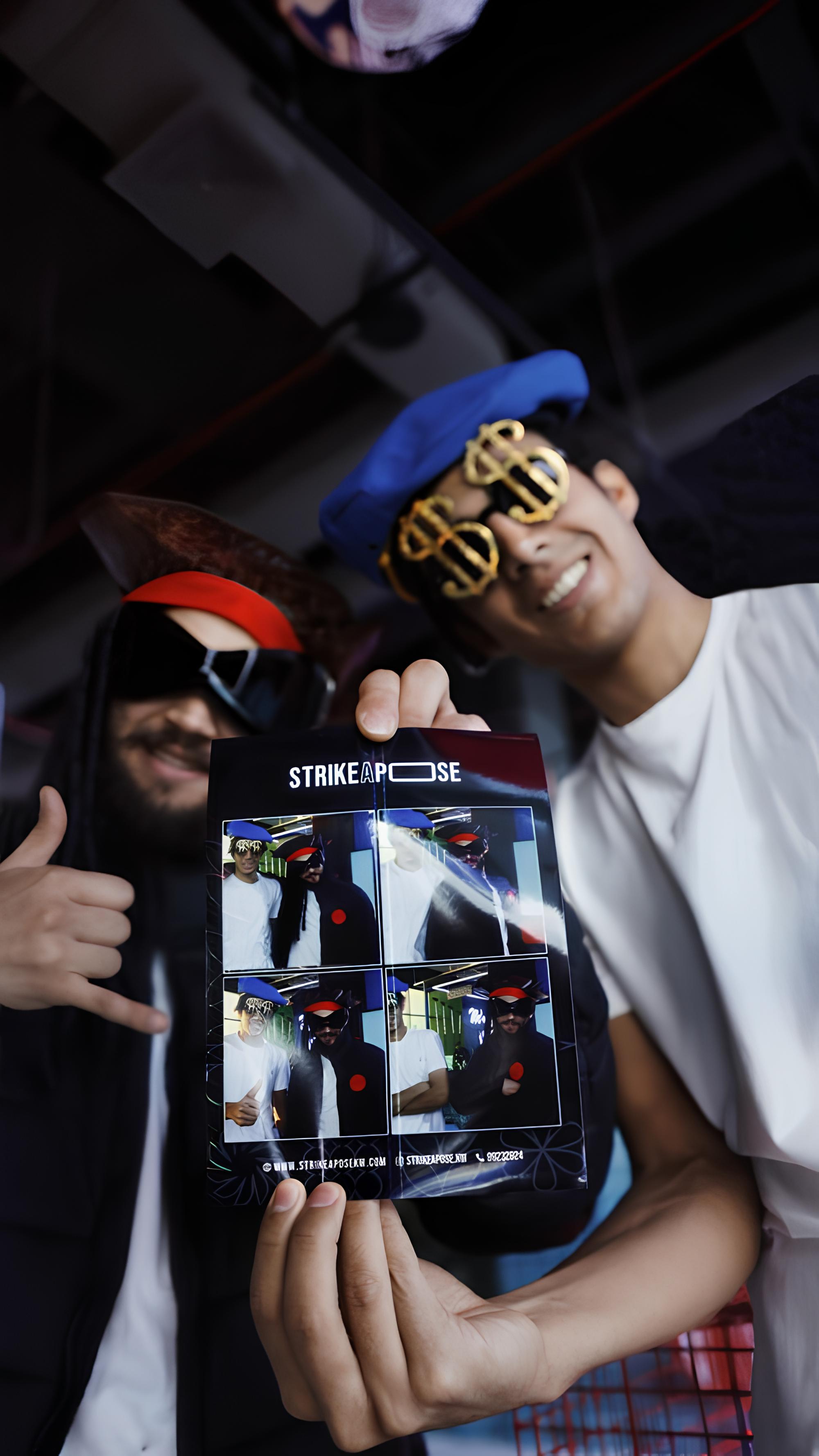 Two young men wearing novelty pirate and dollar sign glasses holding a photo strip with four different poses.