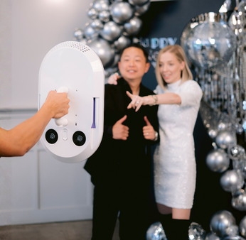Three women in casual clothes interacting with a glowing circular virtual interface on a blue background.