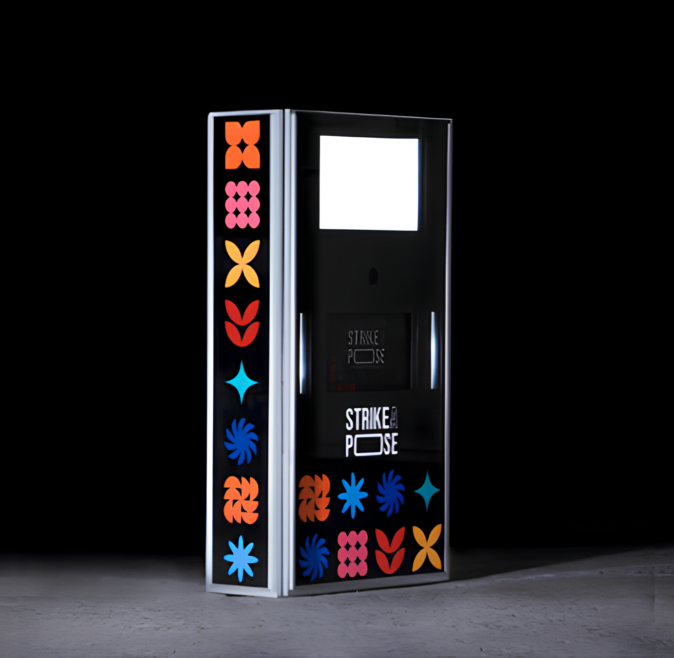 Tall, black digital display kiosk with colorful geometric flower patterns on sides and words 'STRIKE A POSE' on front.