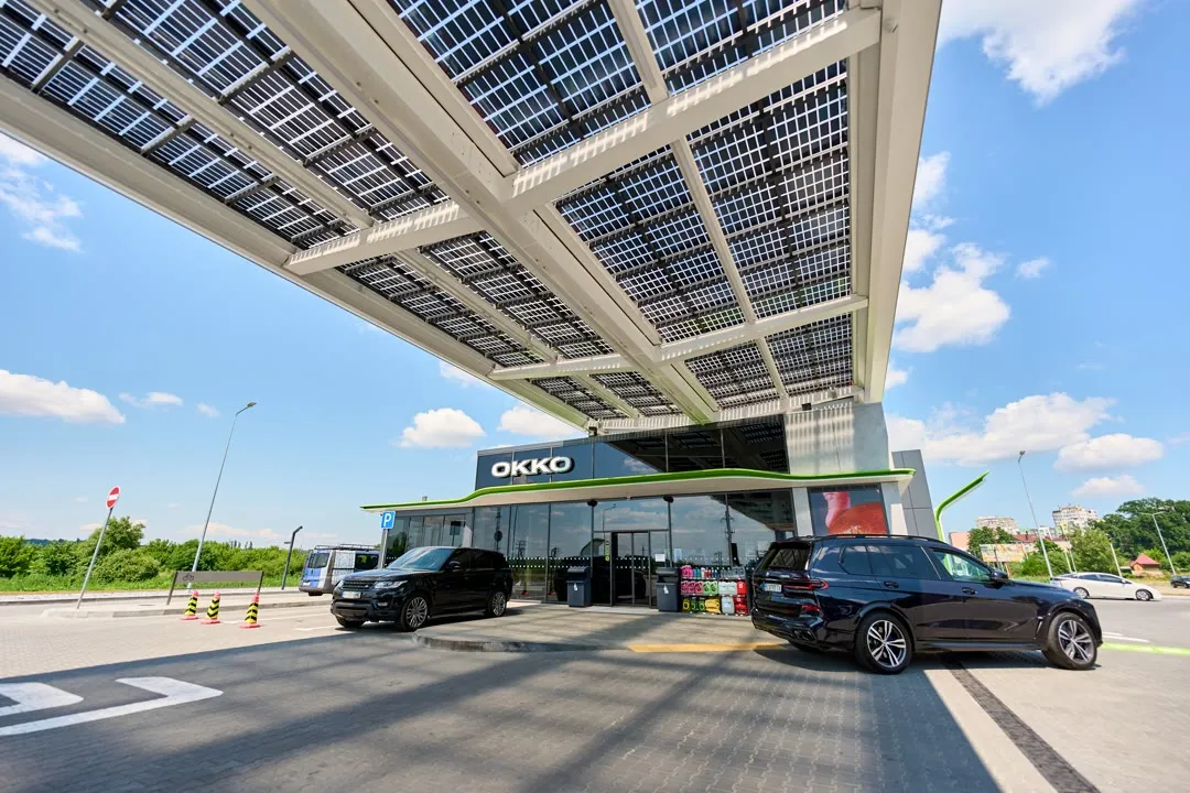 Сучасна станція зарядки електромобілів із чорним автомобілем під навісом під час дня.