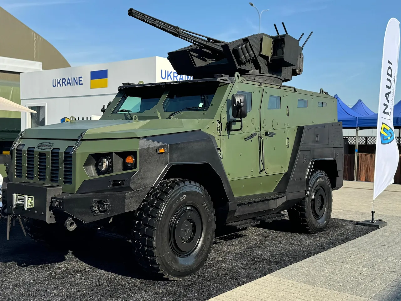 Броньована військова машина зеленого кольору з великокаліберним кулеметом на даху.