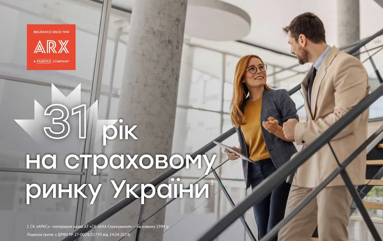 Чоловік і жінка в офісі спускаються сходами, розмовляючи і посміхаючись.
