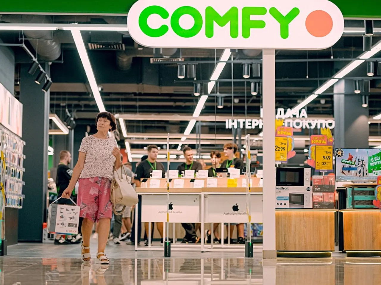 Вхід до магазину Comfy з великим зеленим вивіскою та яскравим червоним об’єктом на екрані.