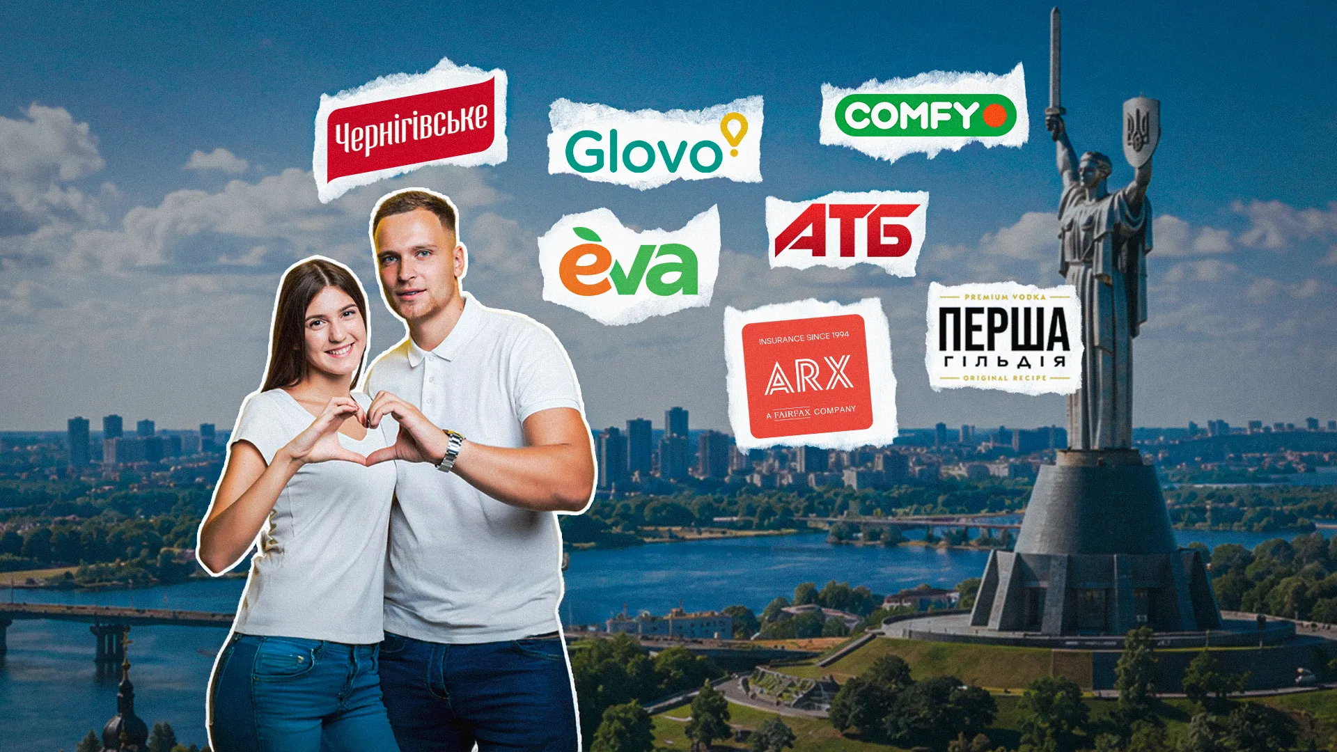 Парa в білій одежі робить серце руками на фоні пам’ятника Батьківщини-матері й логотипів брендів.