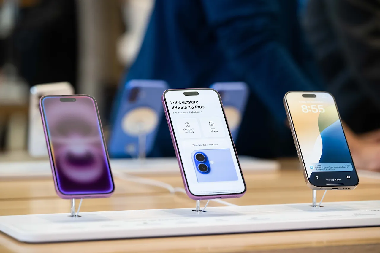 Три сучасні смартфони iPhone, розставлені на підставках у магазині.