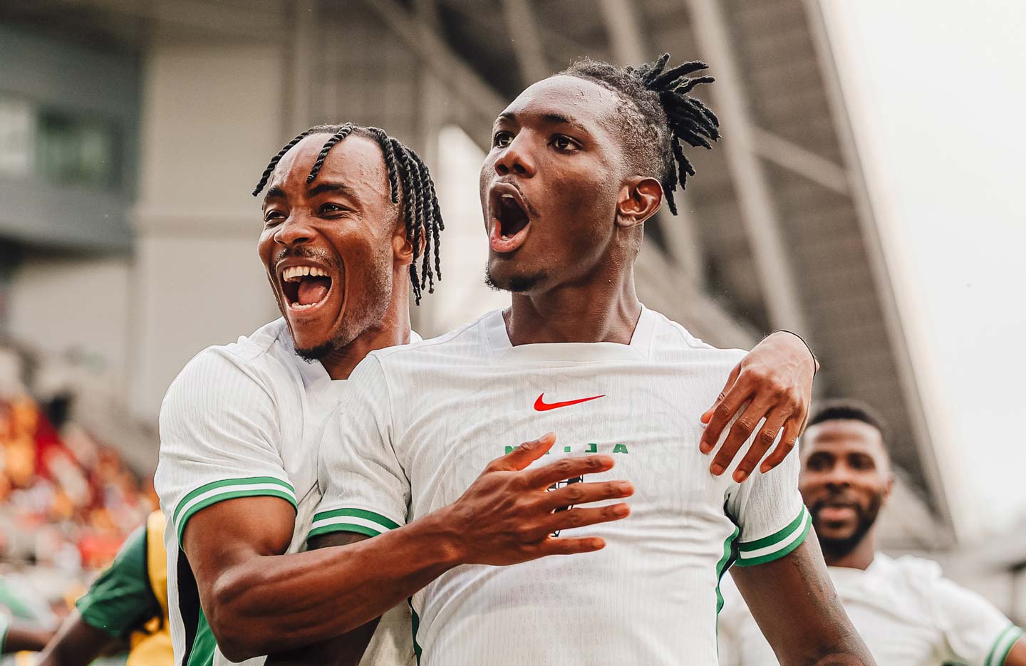 Two Nigerian Super Eagle football players celebrating after scoring a goal