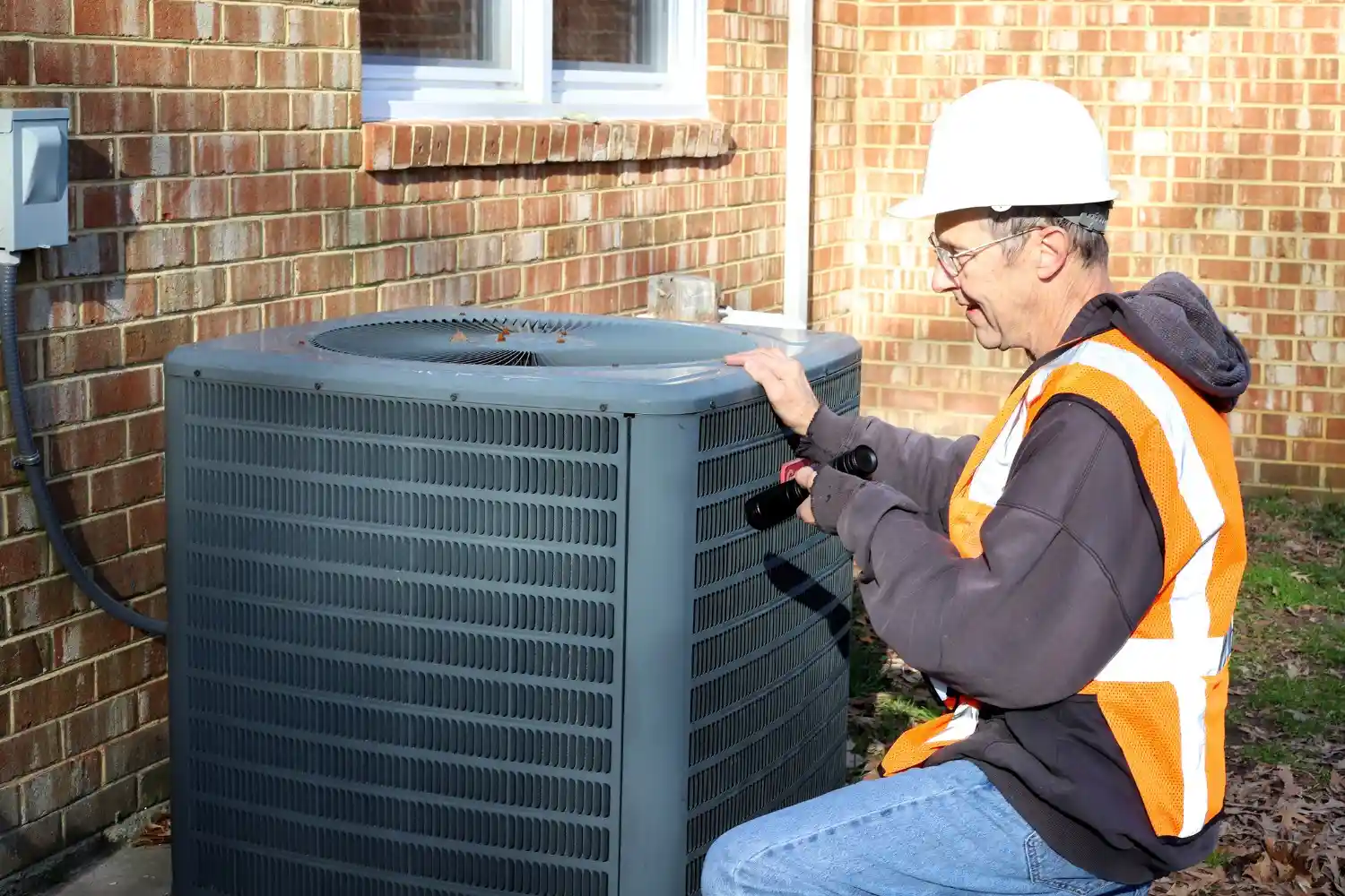 Technician cleaning or checking HVAC unit.