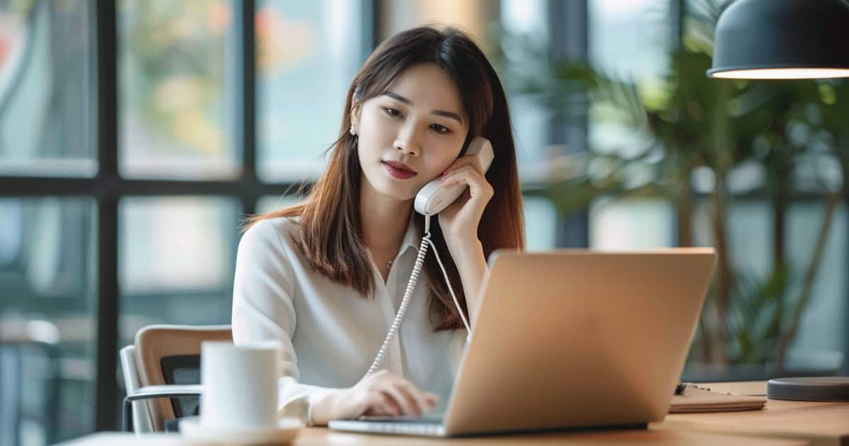 Professional using a modern VoIP phone system at a clean office desk setup.