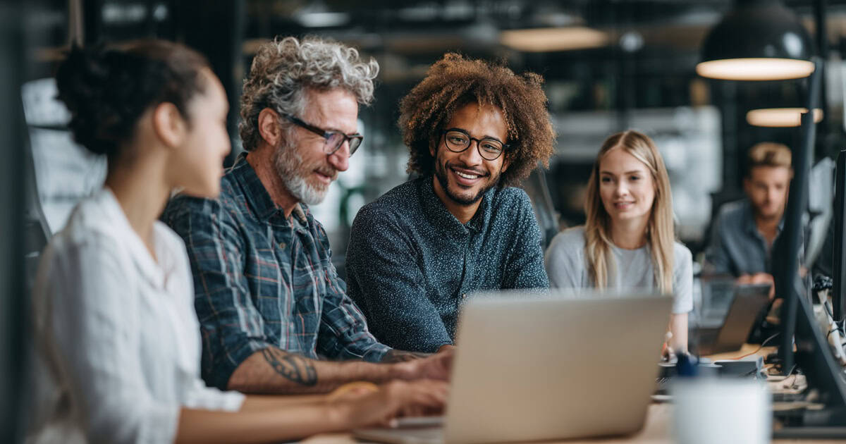 Small business employees working with an IT technician to troubleshoot technology in a modern office.