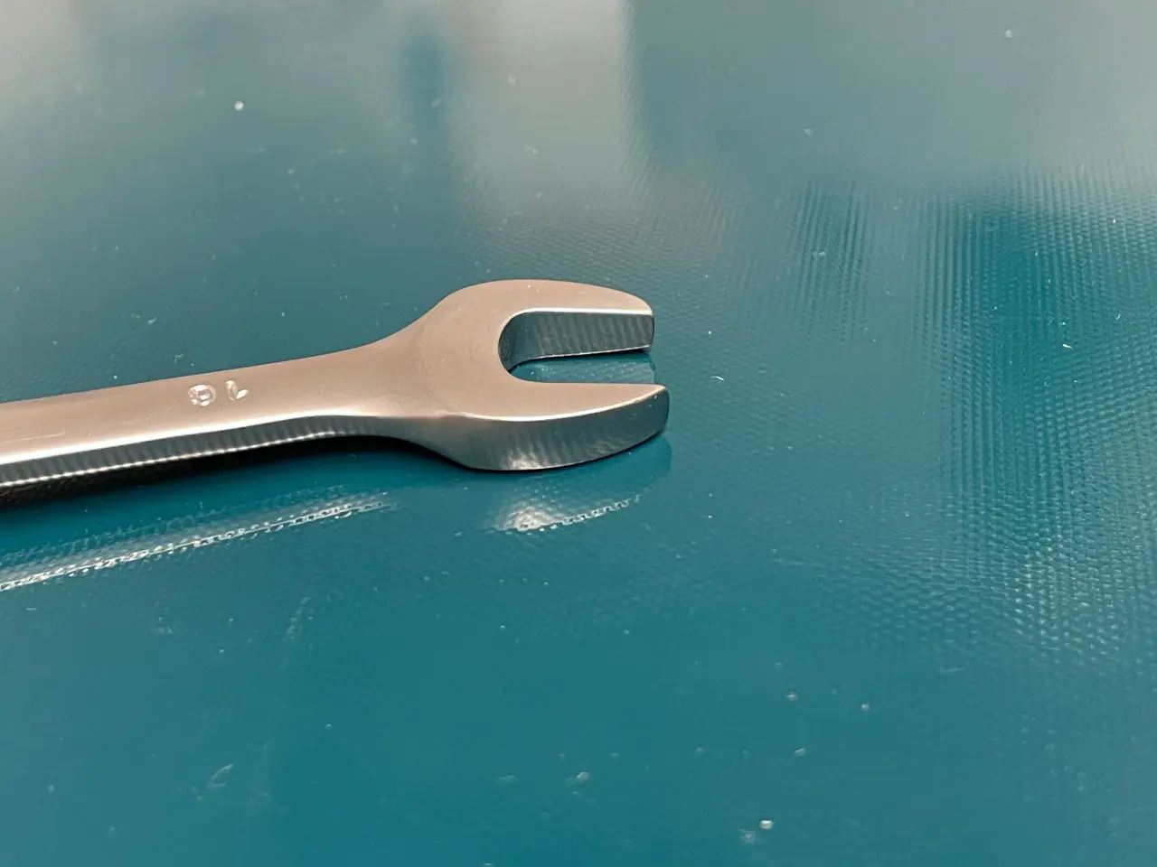 Wrench on a teal colored case conveyor belt. 