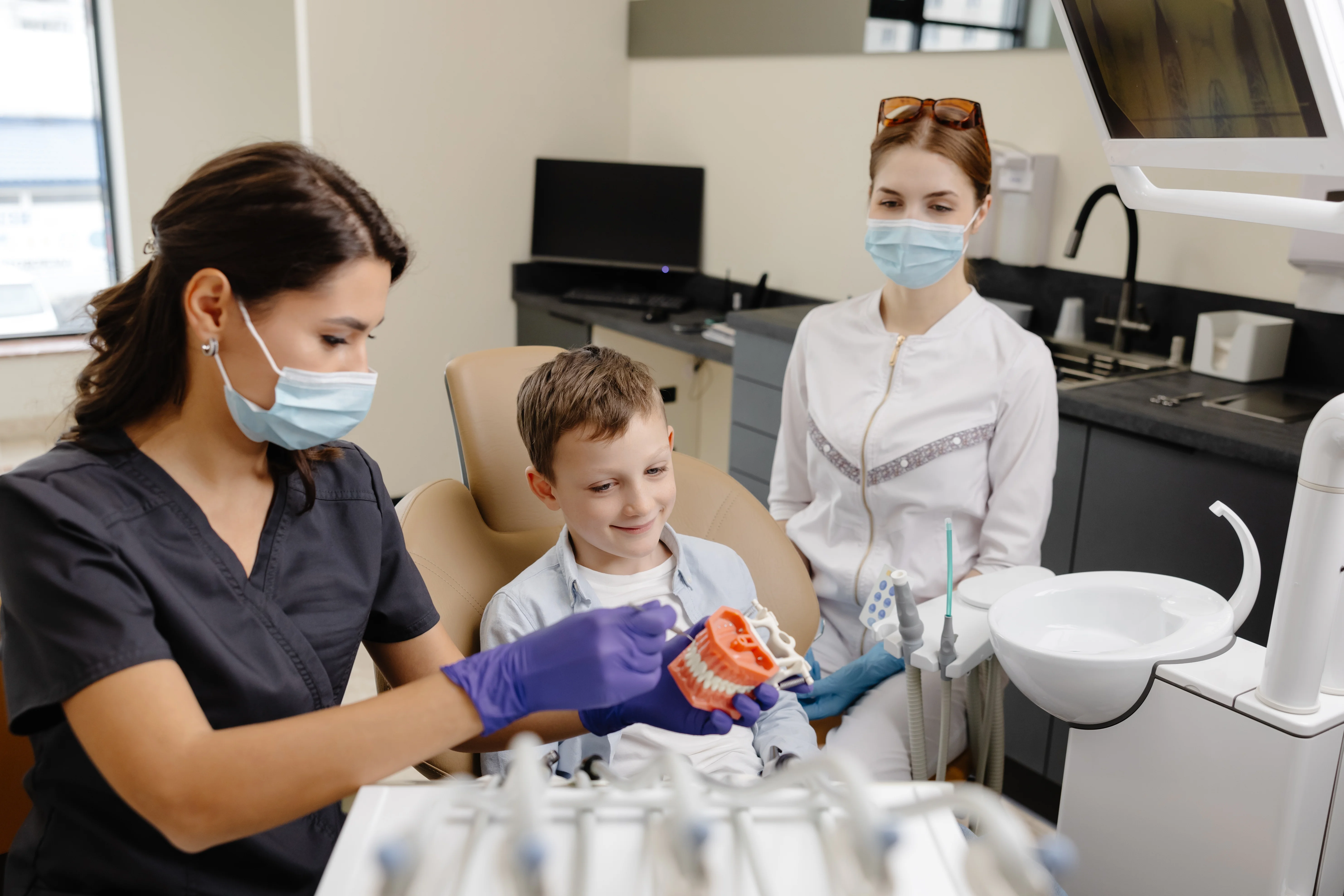 Young boy examining a teeth model during a family dental visit