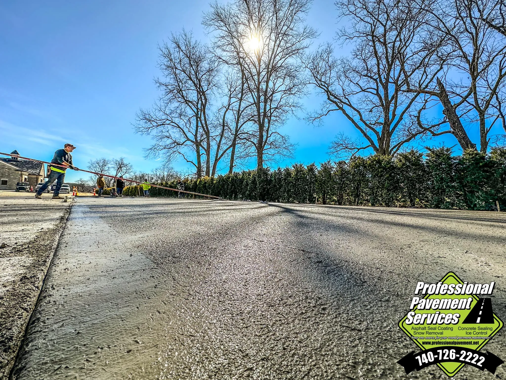 A worker levels freshly poured concrete under a bright sky, with a "Professional Pavement Services" logo visible.