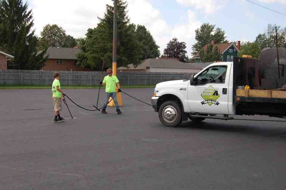 professional applying hot-pour crack sealant to asphalt surface - asphalt maintenance columbus