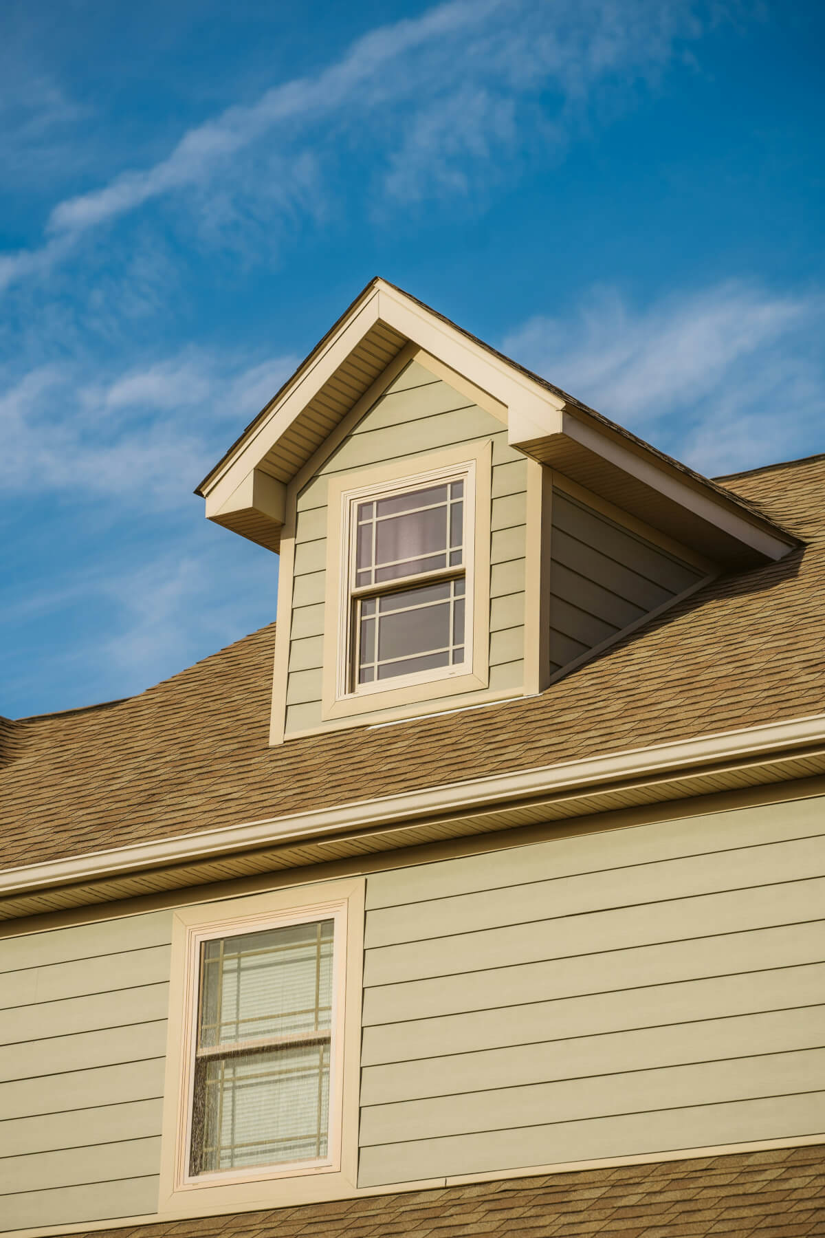 Residential house viewed from below, focusing on the pitched roof with shingles