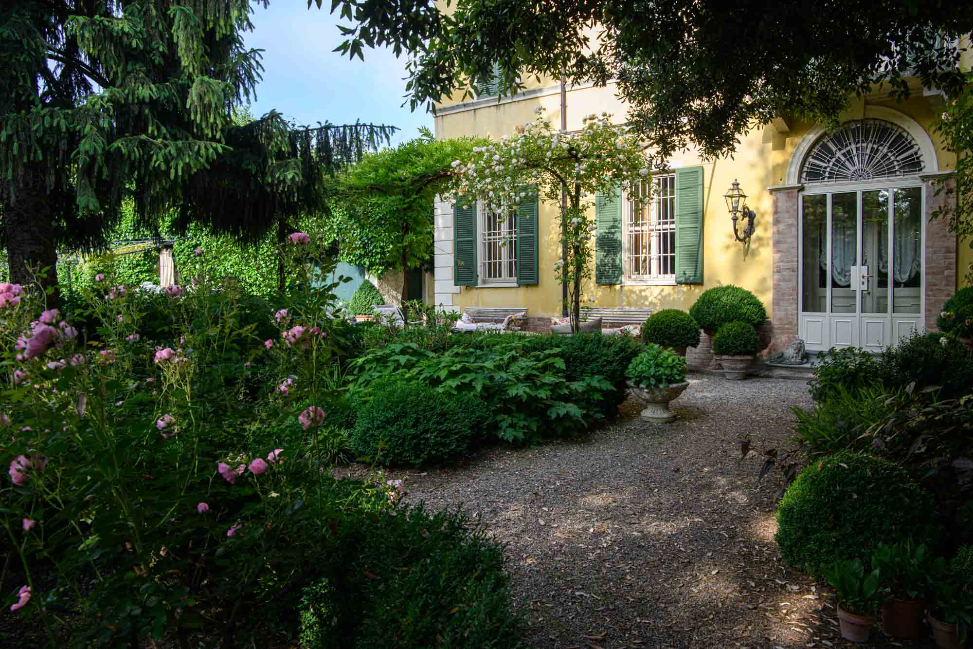 Blooming garden of an elegant Italian villa, rich with roses and manicured greenery, inviting slow strolls and moments of quiet countryside bliss.