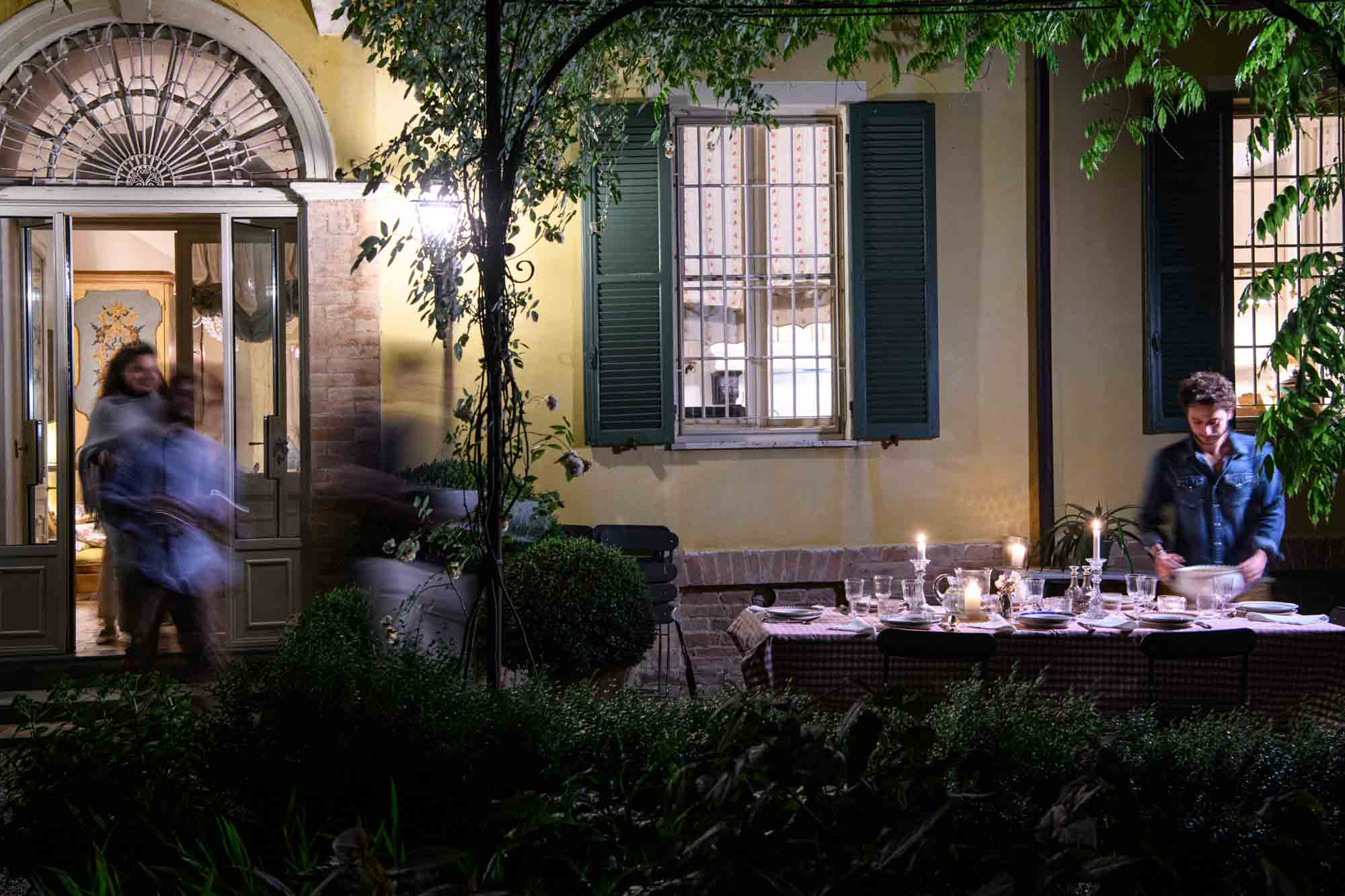 Al fresco dining in the candlelit garden of an elegant Italian villa, evoking the charm of la dolce vita and slow summer evenings in the countryside.