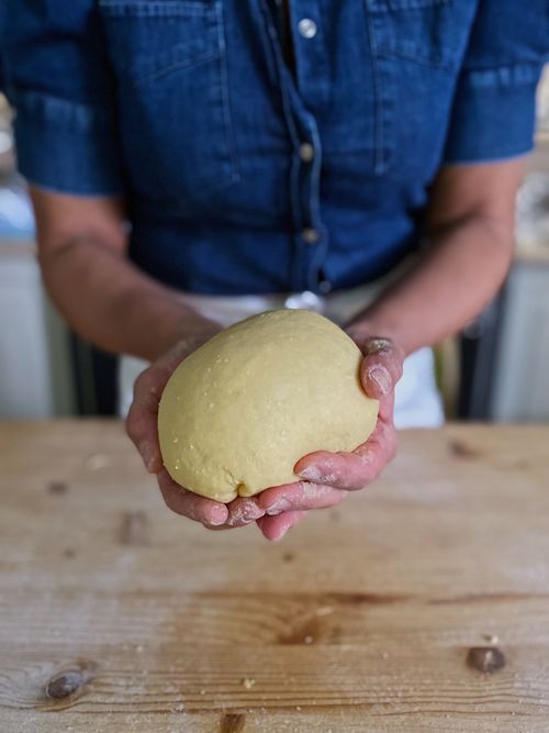 Hands holding fresh homemade pasta dough during an authentic Italian cooking class in a countryside villa.