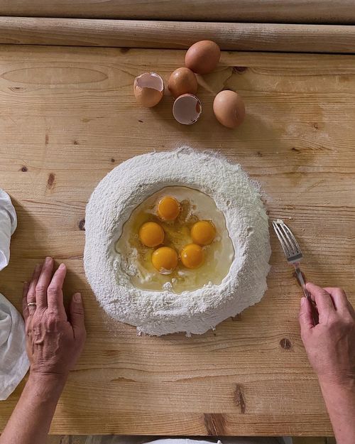 Flour well with fresh eggs ready to be kneaded, captured during an authentic pasta-making class in Italy.