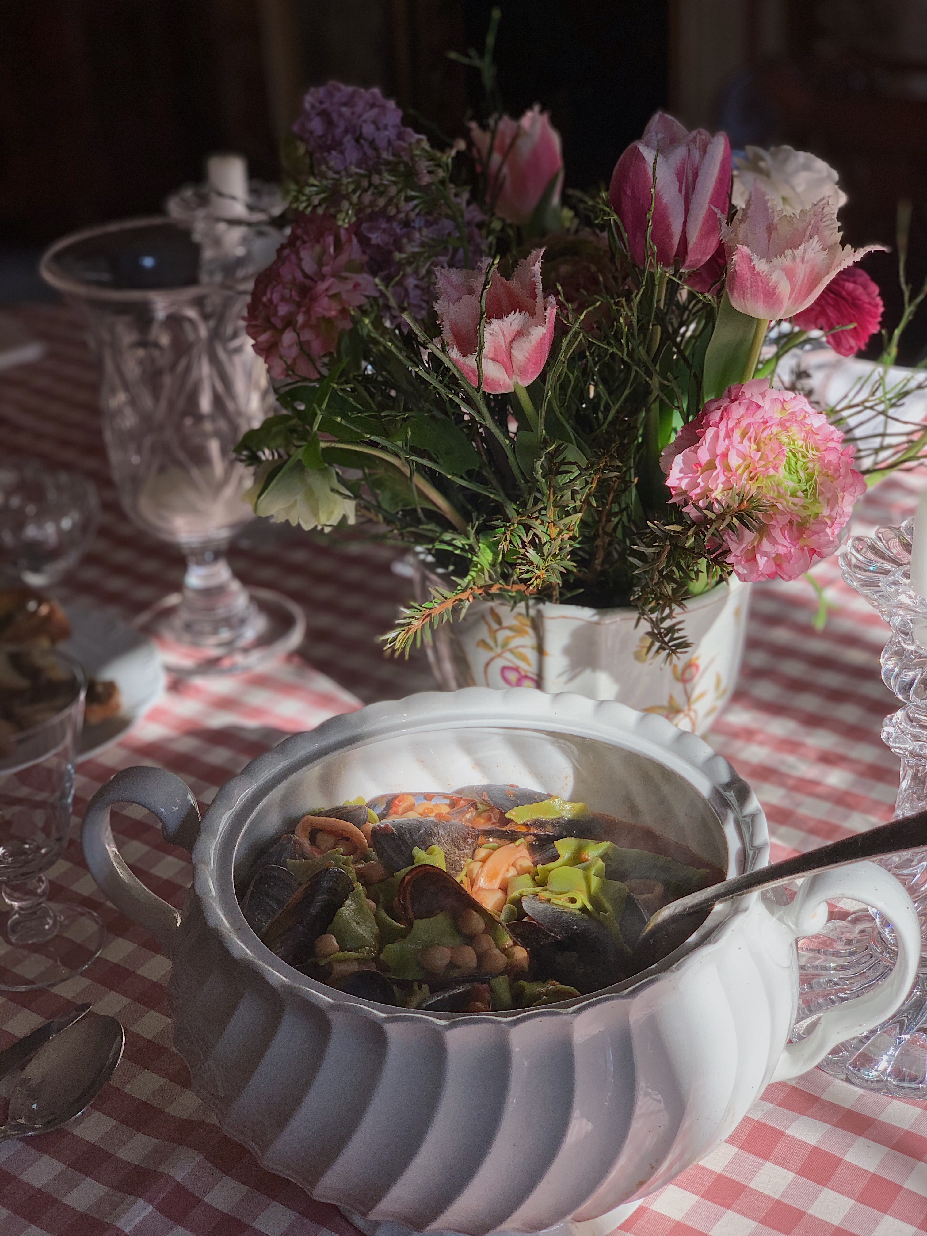 Italian seafood and chickpea stew served in a white ceramic tureen on a floral table, part of a traditional villa lunch.