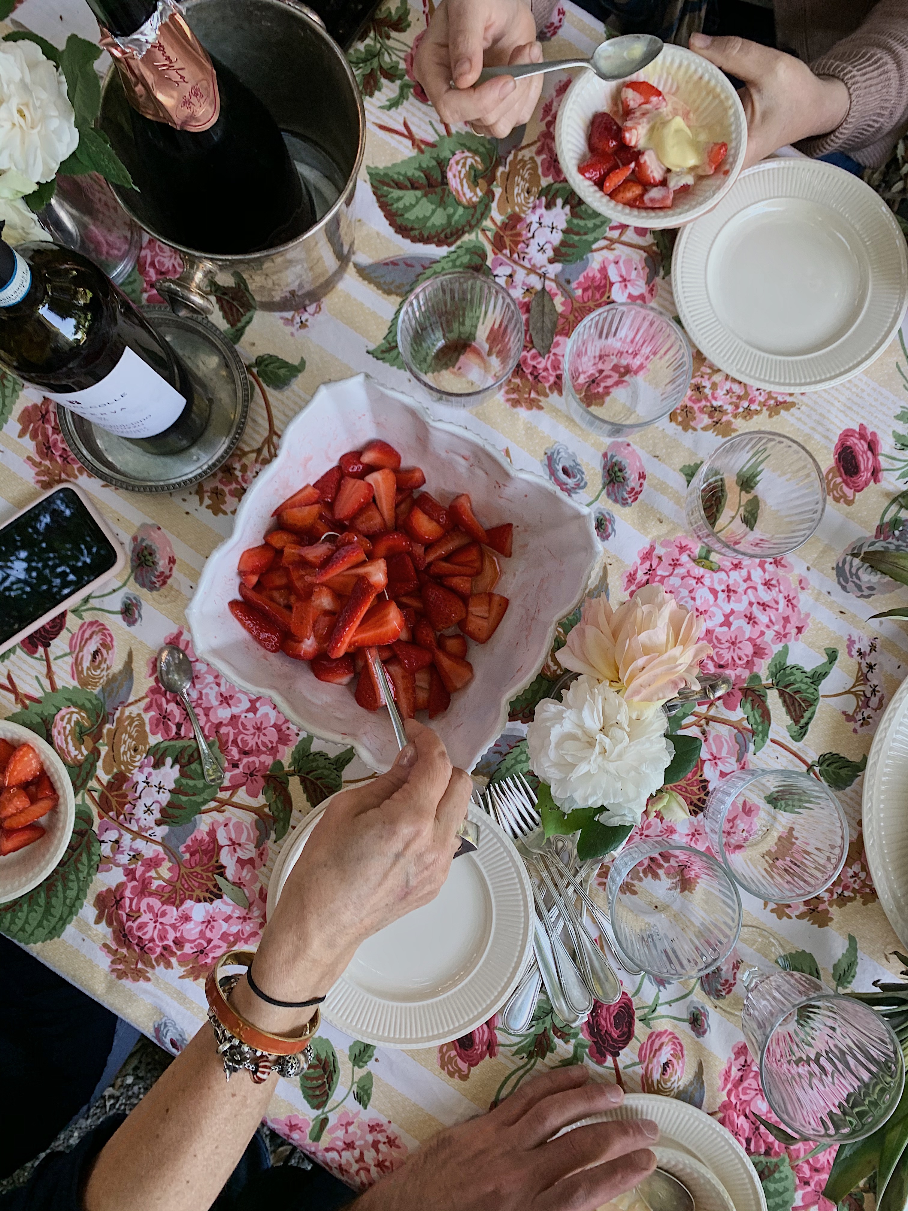 Shared dessert of strawberries and cream enjoyed outdoors in an Italian cooking class with local wines and laughter.