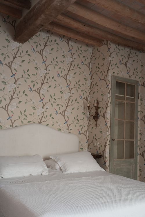 Charming rustic bedroom with floral wallpaper and vintage details, ideal for an authentic Italian countryside experience.