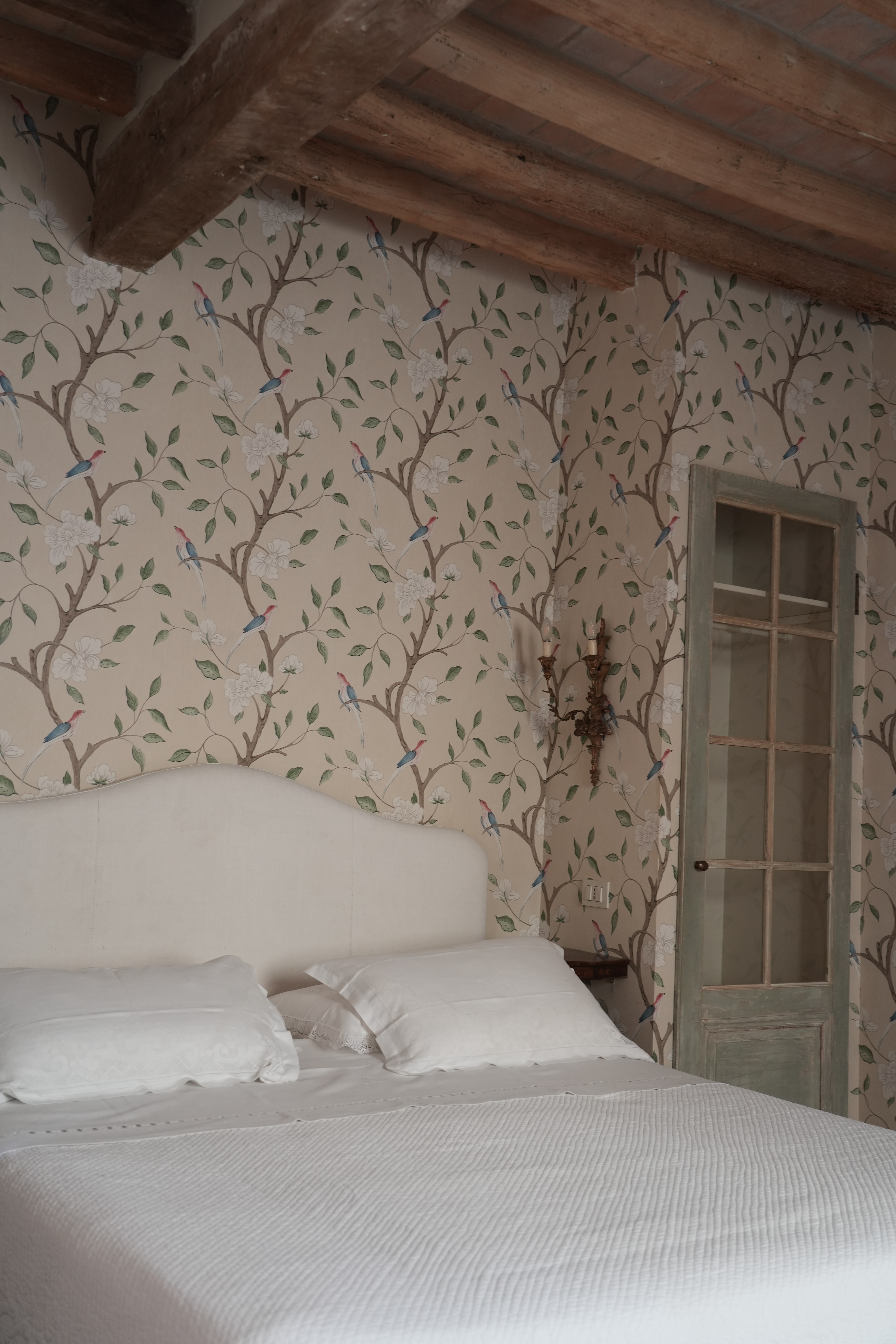 Charming rustic bedroom with floral wallpaper and vintage details, ideal for an authentic Italian countryside experience.
