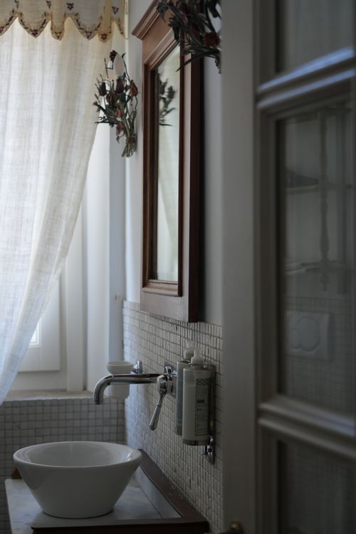 Vintage-inspired bathroom with ceramic sink, natural light and floral accents — charming retreat in the Italian countryside.
