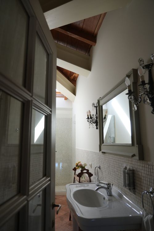 Charming bathroom with exposed wooden beams and vintage decor — refined rural hospitality in Italy.