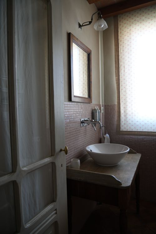 Rustic-style bathroom with ceramic basin and antique wooden table — charming detail in Italian boutique stay.