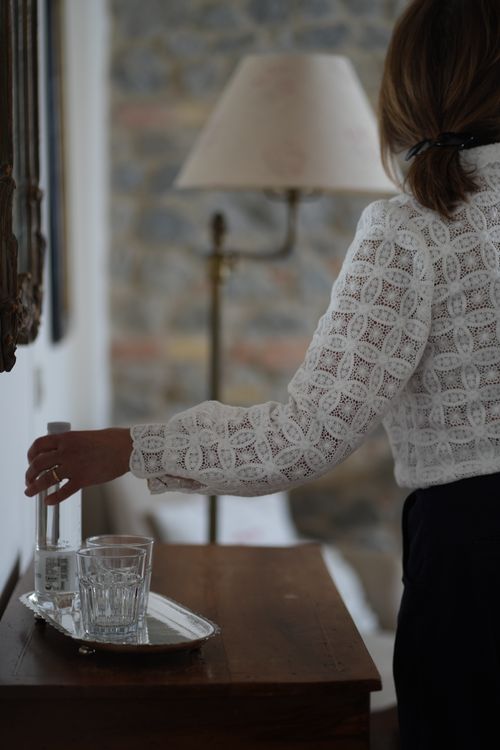 Detail of guest welcome with water and glasses on a silver tray — elegant hospitality in a country house setting.