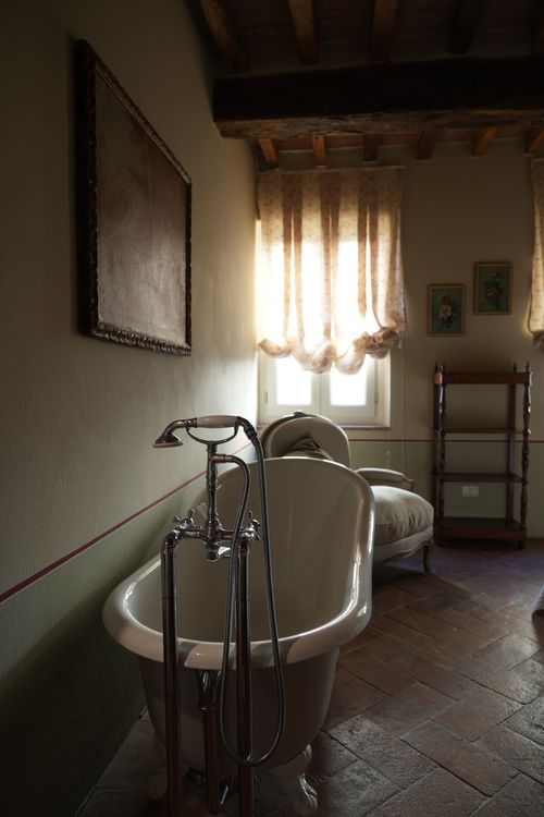 Freestanding clawfoot bathtub in a charming Italian country home, perfect for a relaxing and exclusive stay immersed in authenticity.