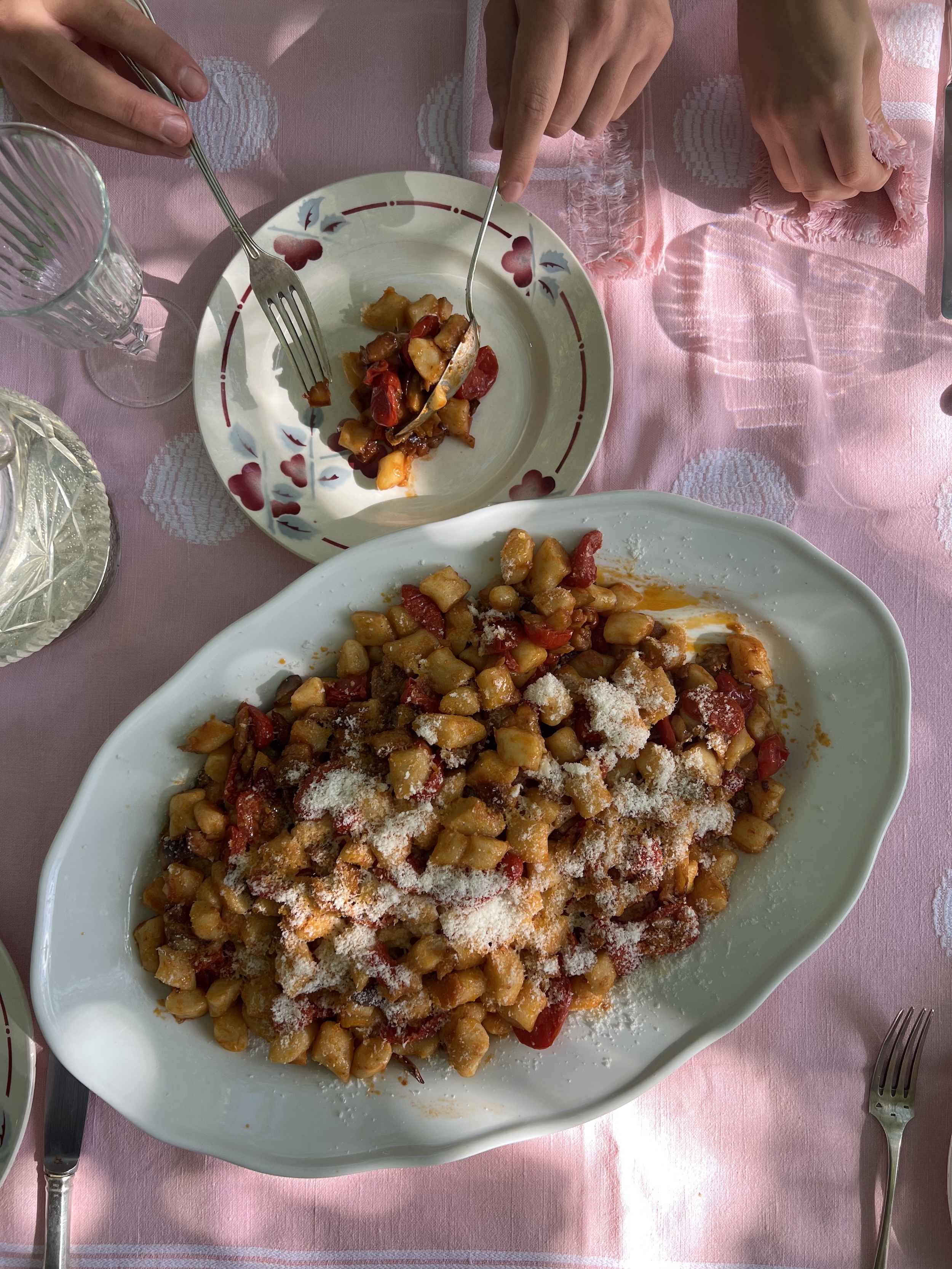 Homemade gnocchi with tomato sauce and Parmesan, served at a family-style table during an Italian cooking experience.
