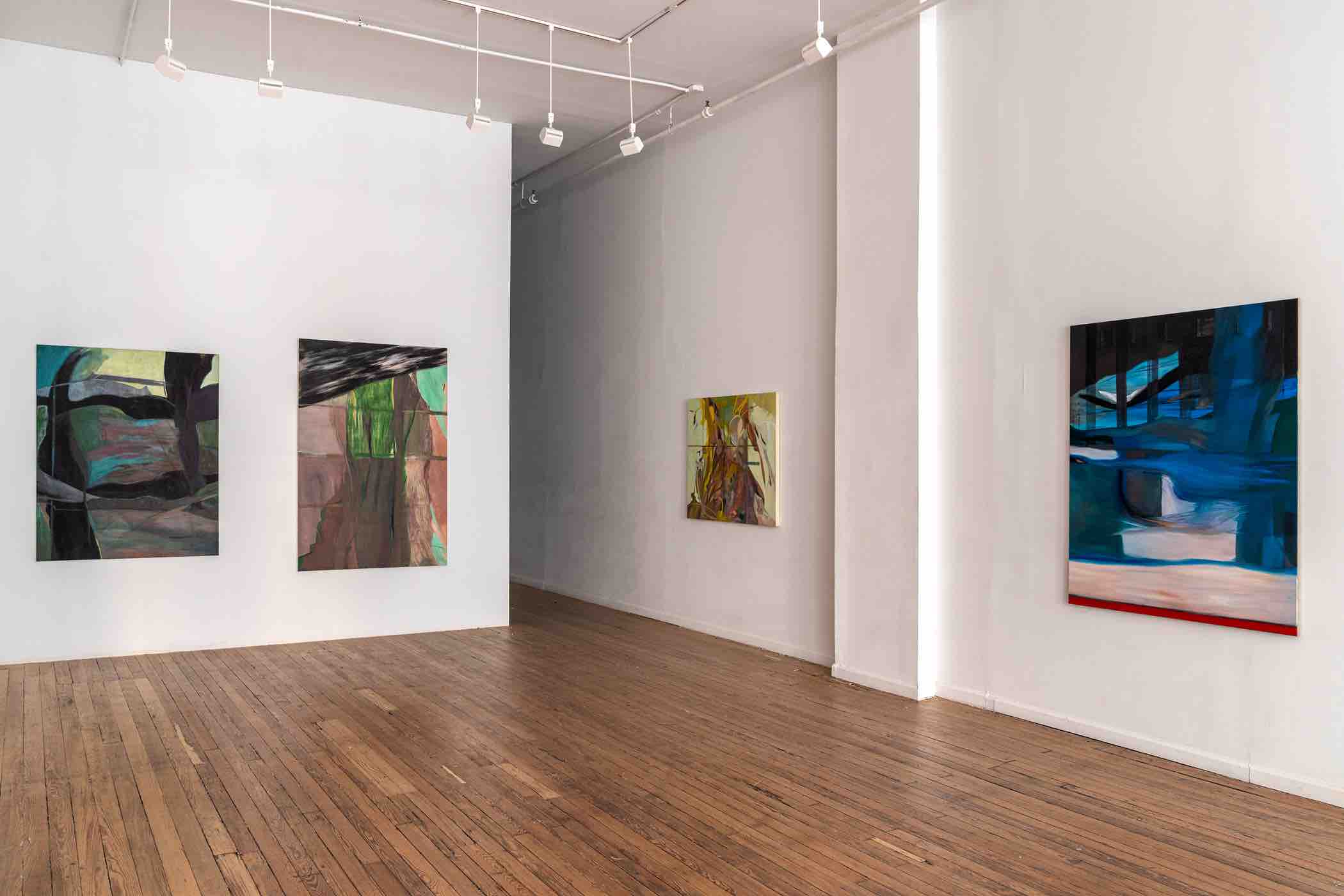 Art gallery interior with four abstract paintings displayed on white walls and wood flooring.