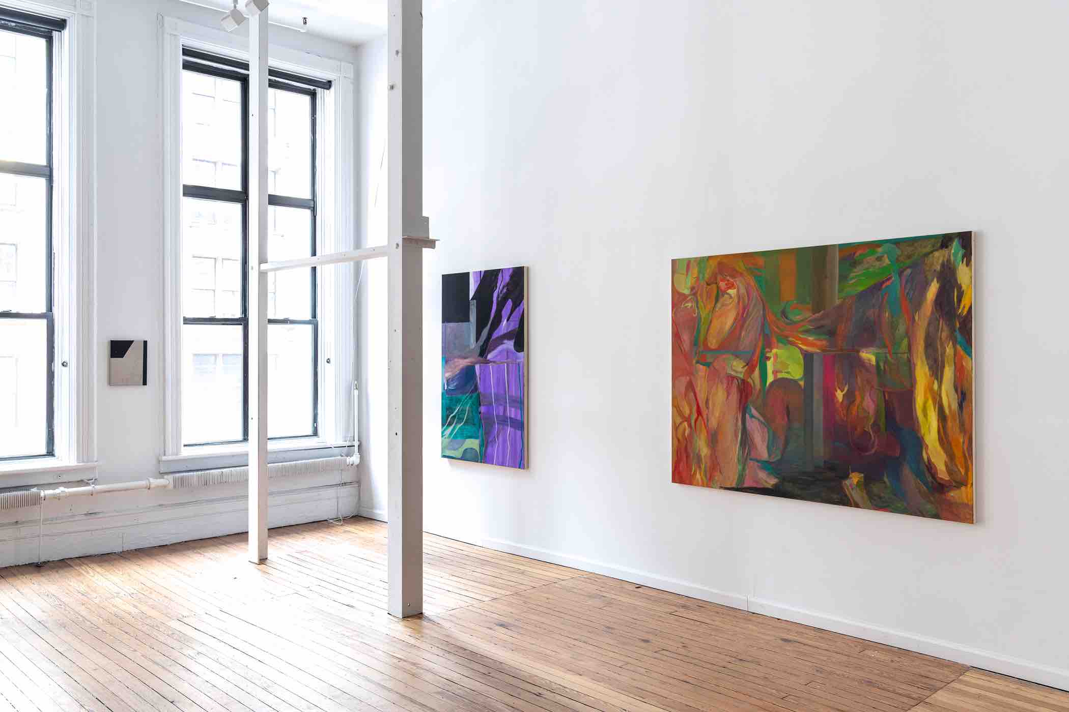 Bright art gallery with wooden floor, large windows, and colorful abstract paintings on white walls.