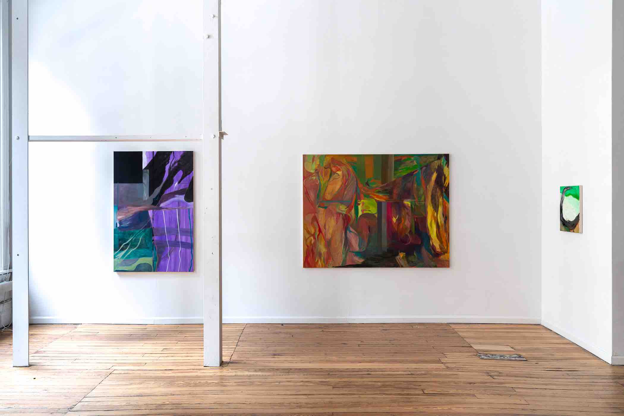 Gallery space with three abstract paintings on white walls and wooden floor.