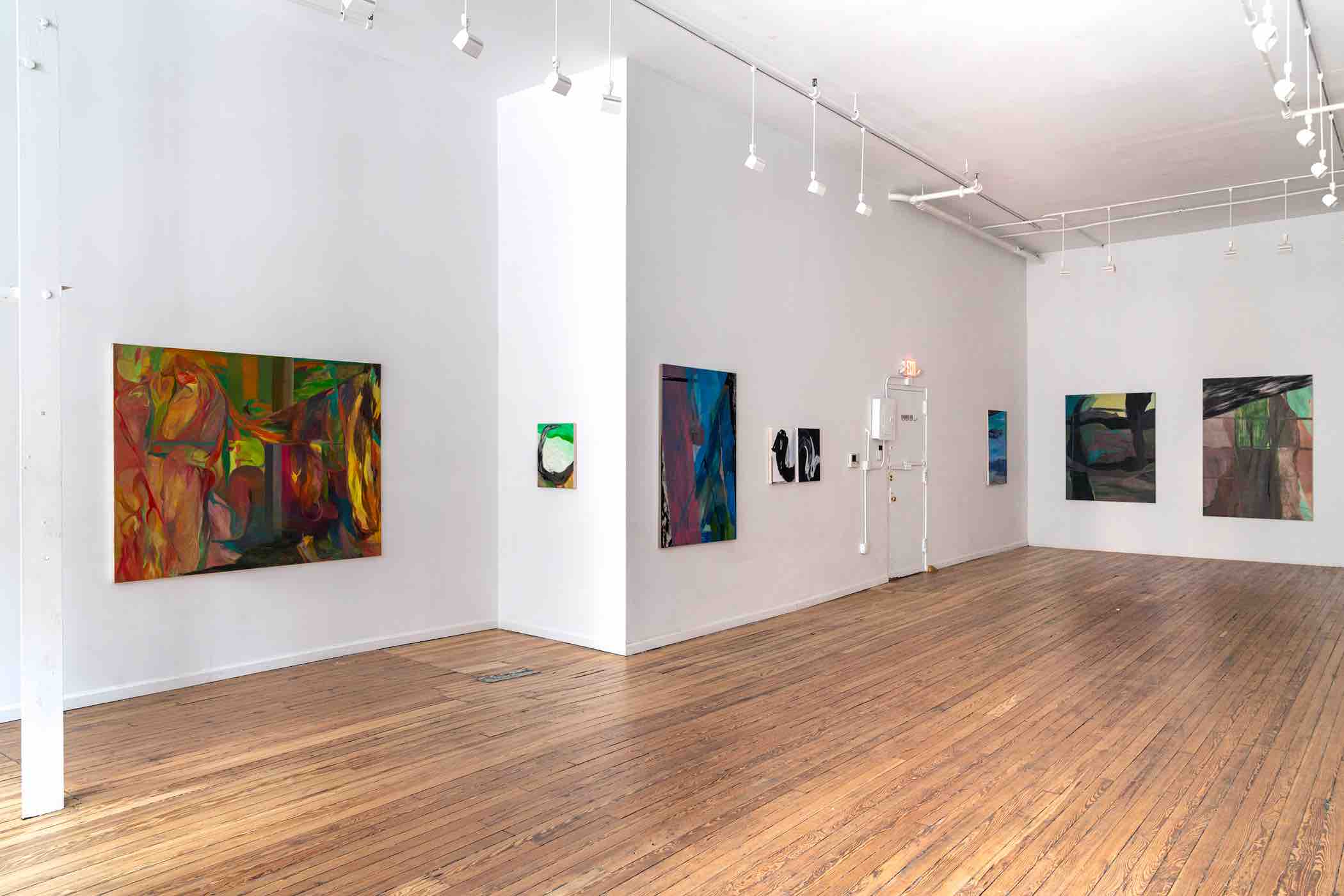 Minimalist art gallery interior with wooden floor and various abstract paintings on white walls.